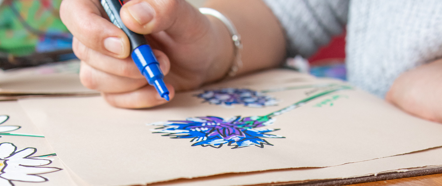 blue and purple illustration of a flower in progress lady holding blue paint marker