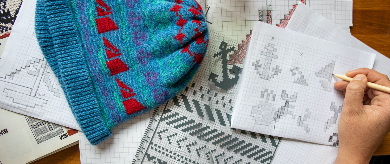 Designing patterns for knitwear , a blue and red knitted hat with green hints rest on a table